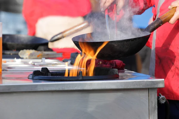 Cooking pasta with meat on a hot frying pan. Street food festival