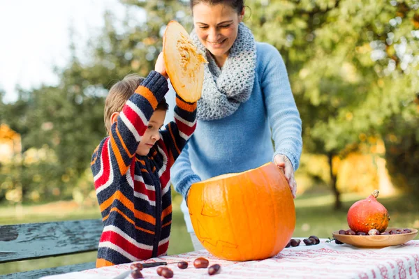 Mother and child opening lid on Halloween pumpkin