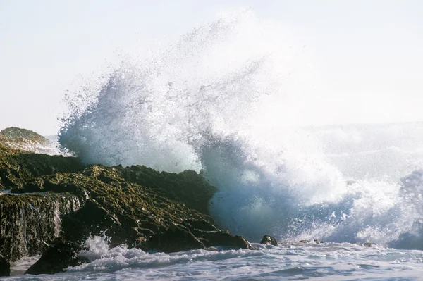 Big ocean wave smashing against a rock