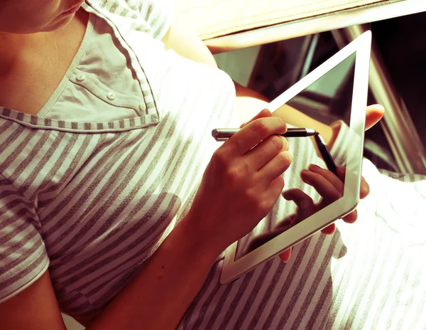 Girl in a striped shirt with a tablet computer and a stylus. Soft and sunny. With reflection.