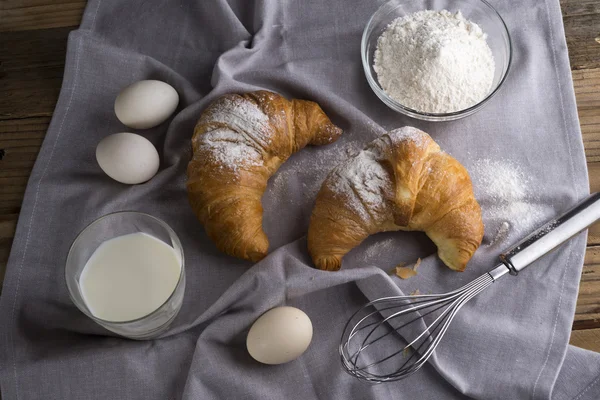 Still life of croissants, eggs, milk and flour. Rustic style.
