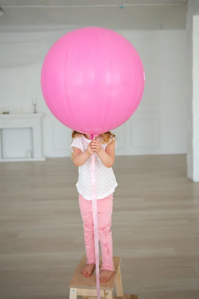 The girl hid behind a big balloon