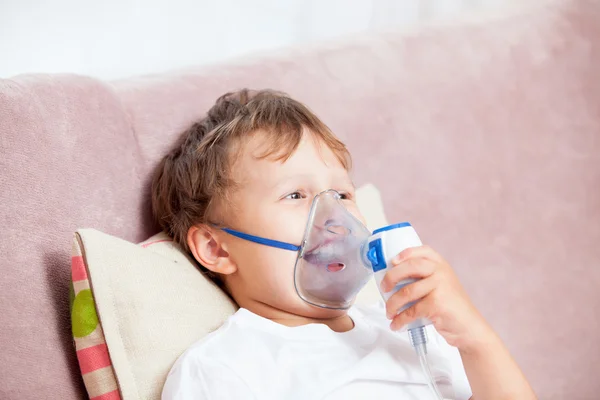 Boy making inhalation with a nebulizer at home