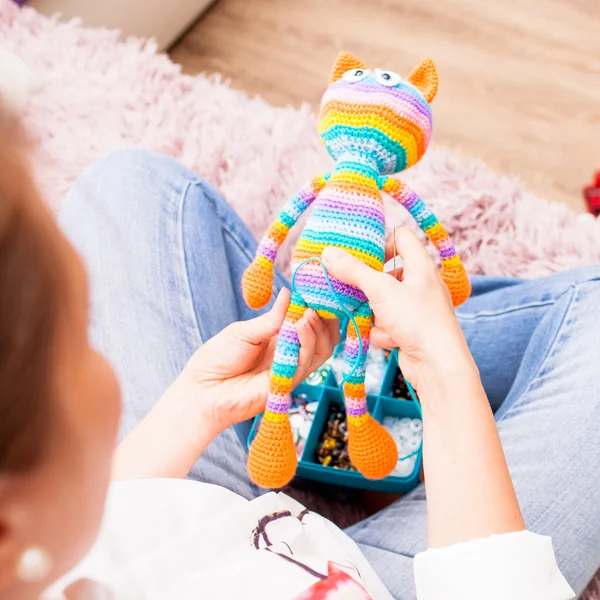 Young woman is engaged in needlework, to sew toys amigurumi leg