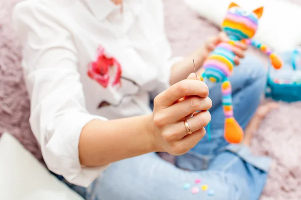 Young woman is engaged in needlework, to sew toys amigurumi leg
