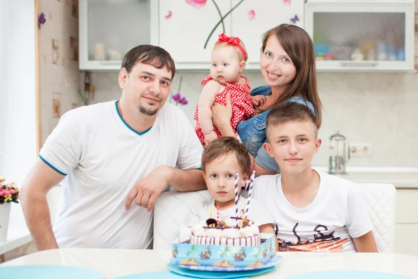 Happy family in the kitchen at the table with the cake