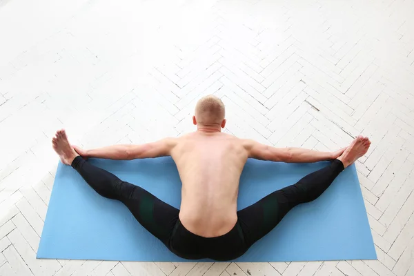 Man practicing yoga. Upavistha konasana. Wide-Angle Seated Forward Bend.