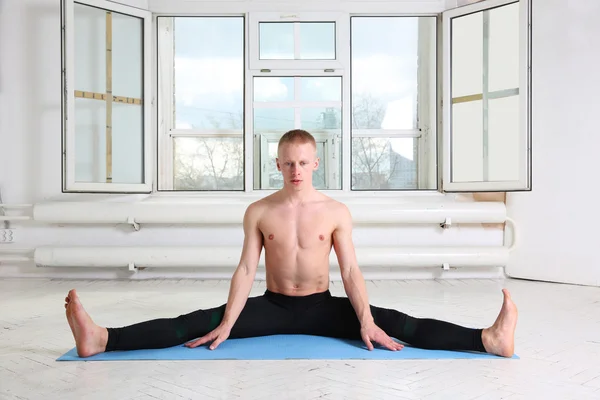 Man practicing yoga in white room with big window