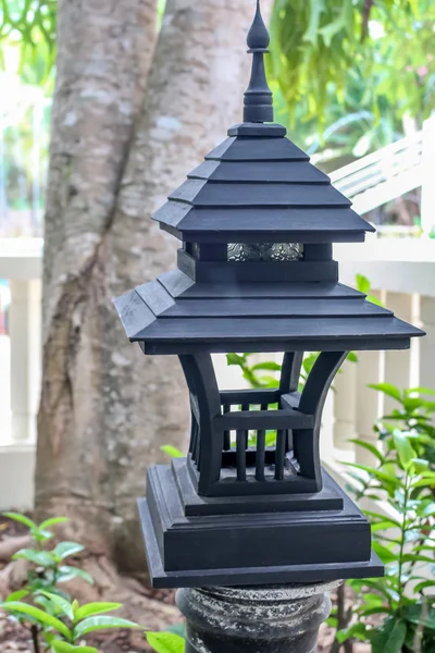 Black woodern lantern lamp with light bulb inside in the green garden forest environment