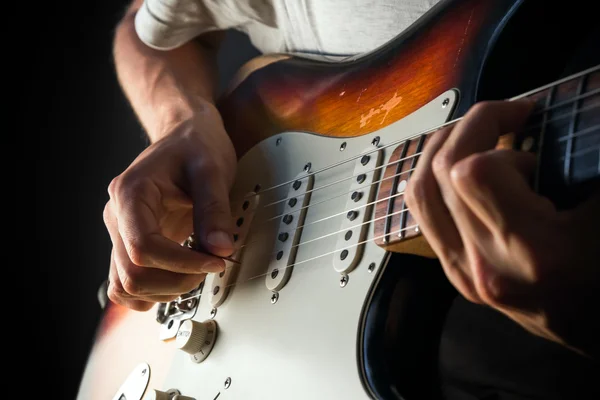 Vintage electric guitar closeup, male hands playing with a pick