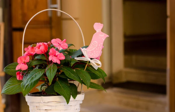 Decorative White wicker flowerpot with natural flowers  and leaves with pink decorative wooden bird