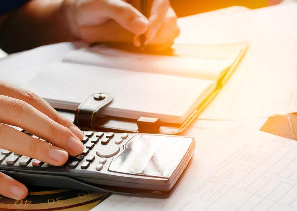 Close up, business man or lawyer accountant working on accounts using a calculator and writing on documents, soft focus