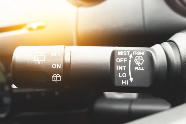 Closeup shot of male driver adjusting speed of screen wipers in car