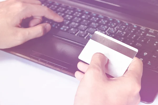Man's hands using a laptop at home while holding credit card, on-line shopping at home