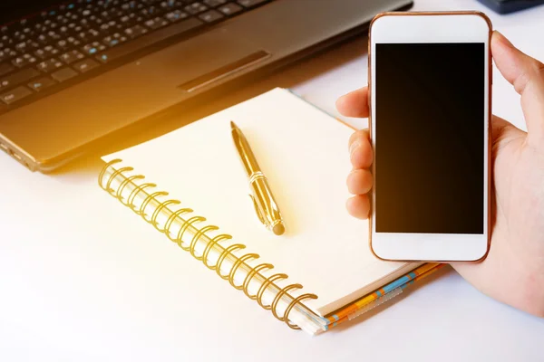 Close up of a men using smart phone with blank mobile and calculator, pen, notebook. Smart phone with blank screen with clipping path. Hand using a white smart phone on a desk at home, soft focus.