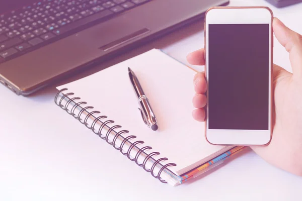 Close up of a men using smart phone with blank mobile and calculator, pen, notebook. Smart phone with blank screen with clipping path. Hand using a white smart phone on a desk at home, soft focus.