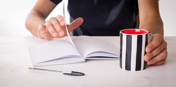 Male hands on a table with mug and books