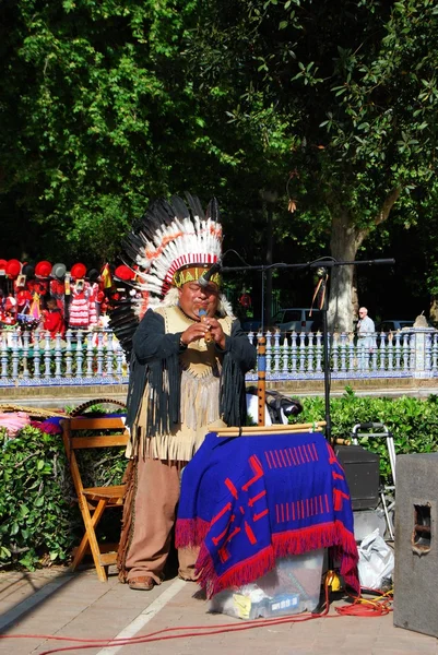 Man dressed as an American Indian playing a musical instrument in the Plaza de Espana, Seville.