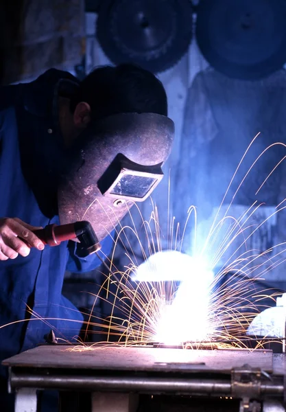 Man welding wearing protective clothing in a workshop.