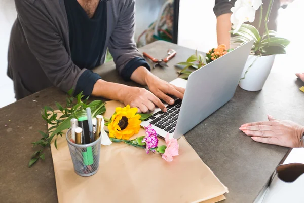 Florist working on laptop with flowers on counter