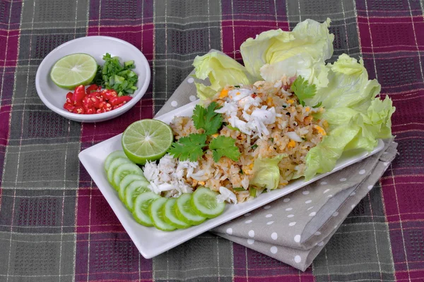 Fried rice with crab topped streamed crab,halve green lemon,sliced cucumber,lettuce and coriander  served  spicy  sour filling side dish. Side view.