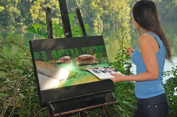 Artist looking at the scenery while painting on canvas