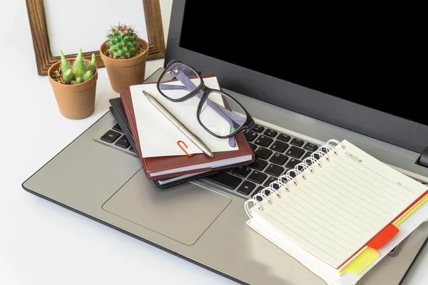 Office desk top view with smartphones, laptop eyeglasses and book.