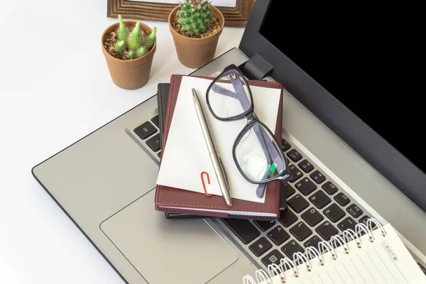 Office desk top view with smartphones, laptop eyeglasses and book.