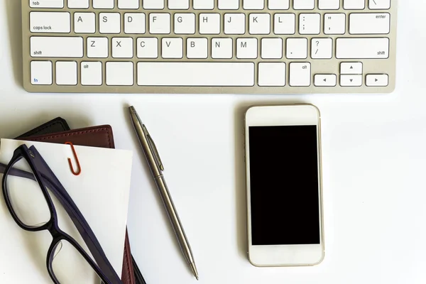 Office desk top view with smartphones, laptop eyeglasses and book.