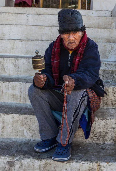 Old man praying outside a temple in Thimphu