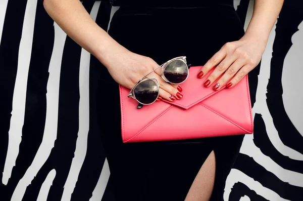 Stylish girl in black dress with pink handbag clutch