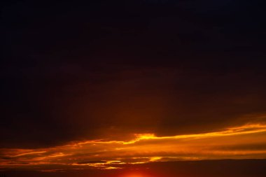 Gün batımında bulutlu bir gökyüzü. Siyah bulutlar arasındaki turuncu ışık çizgisi. Güzel bir doğa manzarası..