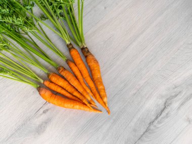 Sadece bahçeden taze havuç. Açık arkaplanda yeşil saplı turuncu havuçlar. İştah açıcı sağlıklı sebze..