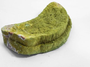 Beyaz arka planda yeşil küfle kaplı bir parça ekmek izole edilmiş..