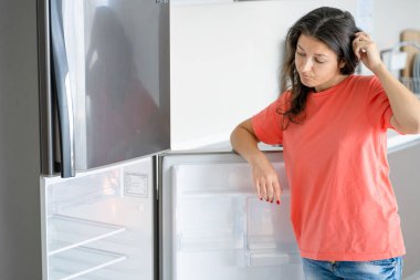 Kız boş buzdolabına şaşırdı. Yiyecek eksikliği. Yemek teslimatı.