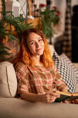 Şirin bir kız sıcak ve rahat bir atmosferde kitap okuyor. Rahatlama ve gizlilik kavramı.