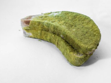 Beyaz arka planda yeşil küfle kaplı bir parça ekmek izole edilmiş..