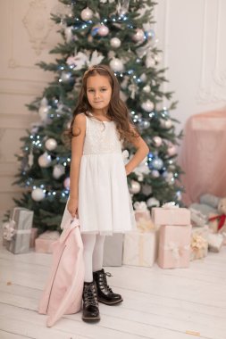 Güzel küçük kız Noel ağacının yanında poz veriyor.