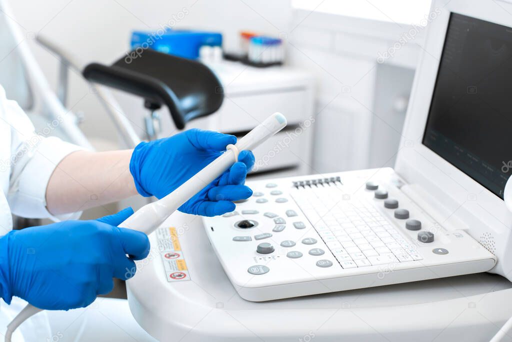 gynecologist doctor prepares an ultrasound machine for the diagnosis of the patient. Applies gel to a transvaginal ultrasound scanner. Women's Health Concept.