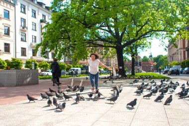 Bir kız şehir meydanındaki güvercin sürüsünü korkutuyor..