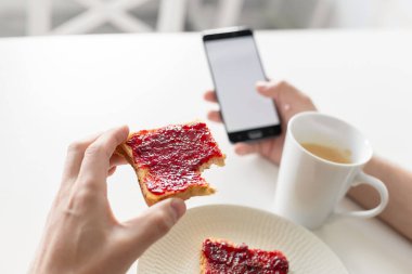 Adam kahvaltıda telefonda haberleri izliyor..