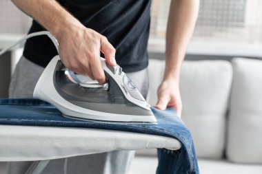 Dışarı çıkmadan önce kıyafetleri ütüleyen bir adam..