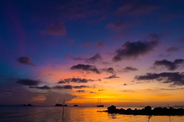 熱帯のビーチでカラフルな夕日 海のオレンジの夕日 熱帯のカラフルな夕日 水の中にセーリング船です マスト付きのシルエットの帆船 — ストック写真