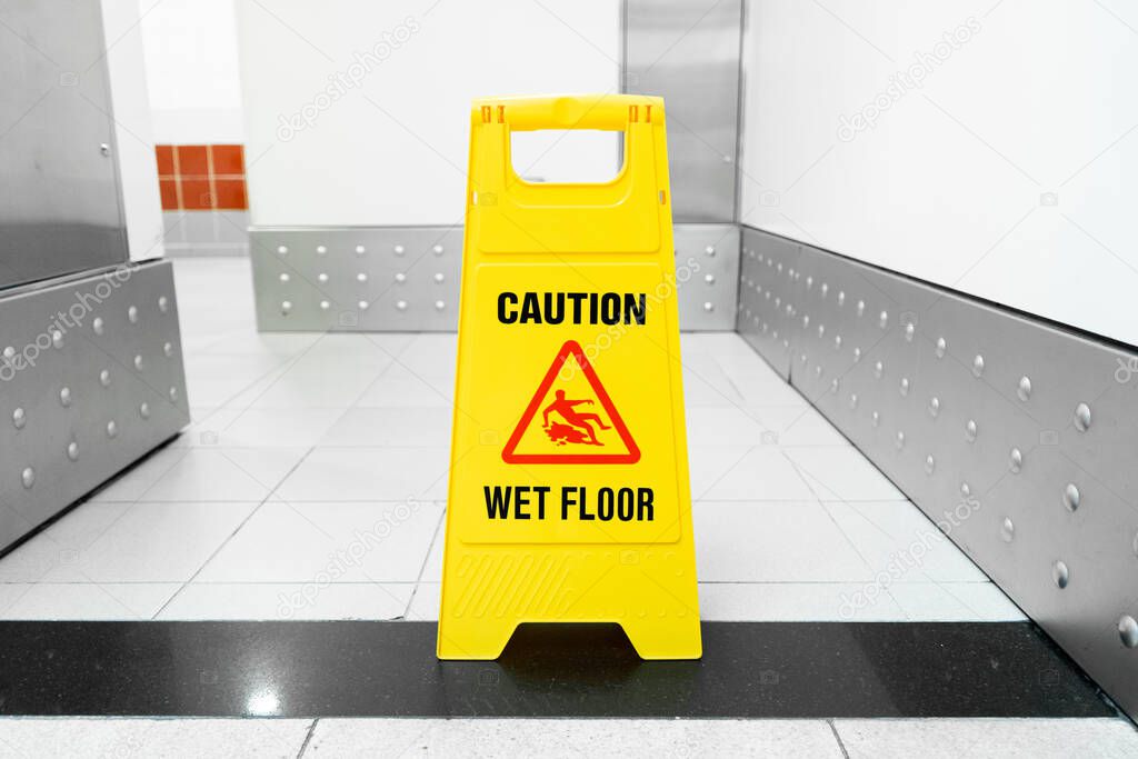 A yellow floor folding sign that draws attention to a freshly washed slippery floor.