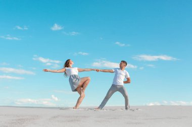 Romantik çift mavi gökyüzü arka planında kum çölünde dans ediyor.