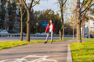 Aktif boş zaman. Sportif bir kız sonbahar parkında paten kayıyor..