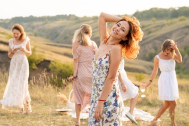 Mutlu bayan arkadaşlarla birlikte tepelerde bir piknikte dans edip eğleniyorlar.