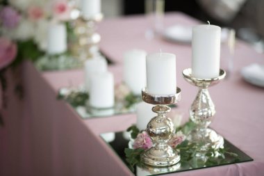 Yeni evliler için düğün sofrası karanfil, gül, anthurium ve okaliptüs yapraklarından oluşan taze çiçeklerle süslenmiştir. Gümüş şamdanlar, beyaz mumlar. Düğün çiçekçisi olarak. Ayrıntıları kapat.