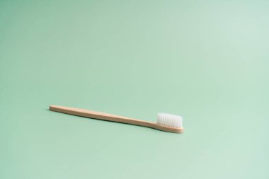 Çevre dostu bambu ahşap antibakteriyel diş fırçası açık yeşil arka planda.