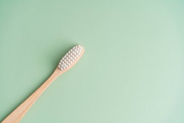 Çevre dostu bambu ahşap antibakteriyel diş fırçası açık yeşil arka planda.
